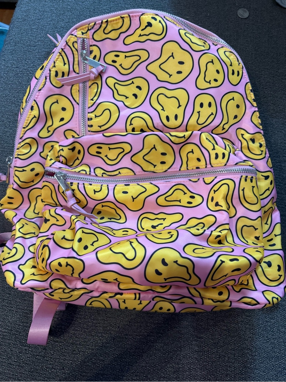 Fun pink backpack covered in yellow warped smiley faces